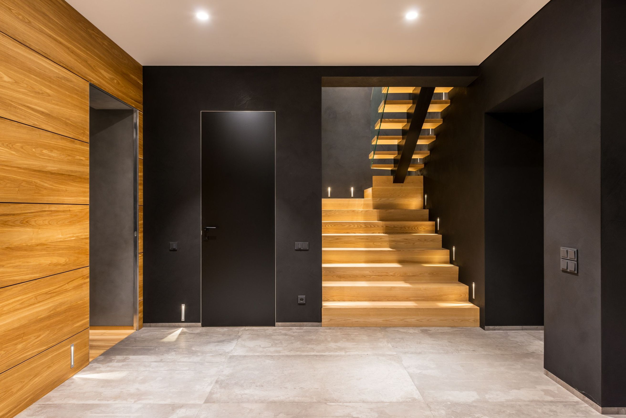 Hallway with lit oak staircase and oak-clad wall